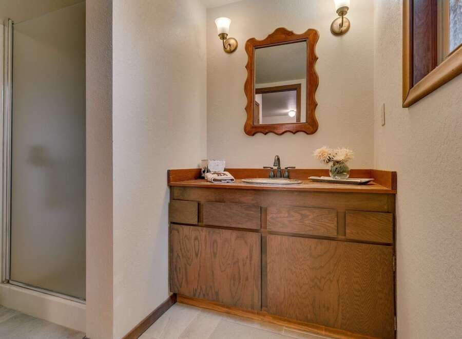 This bathroom features a charming wooden vanity with ample storage, complemented by a decorative mirror and wall sconces.