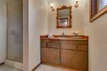 This bathroom features a charming wooden vanity with ample storage, complemented by a decorative mirror and wall sconces.