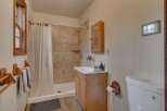 This charming bathroom features a tiled shower with a white curtain, a wooden vanity with a sink, and a toilet.