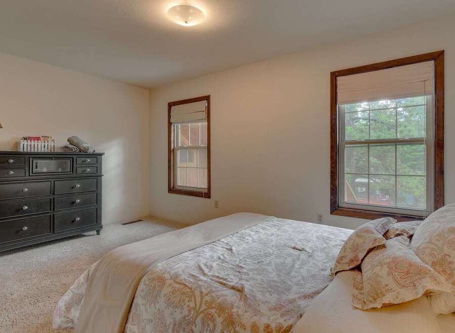 This charming bedroom features a spacious dresser and a comfortable bed adorned with a beautiful paisley comforter.
