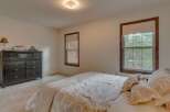 This charming bedroom features a spacious dresser and a comfortable bed adorned with a beautiful paisley comforter.