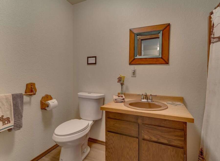 This charming bathroom features a rustic wooden vanity with a warm-toned sink and a decorative mirror above.