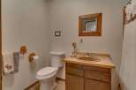 This charming bathroom features a rustic wooden vanity with a warm-toned sink and a decorative mirror above.