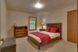This inviting bedroom features a comfortable queen-size bed adorned with plush red pillows and a matching quilted throw.