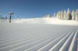 Experience the pristine beauty of a freshly groomed ski slope, perfect for a day of exhilarating winter sports.