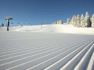 Experience the pristine beauty of a freshly groomed ski slope, perfect for a day of exhilarating winter sports.