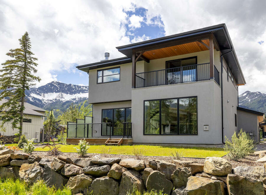 Experience luxury mountain living in this stunning modern home, featuring expansive windows that frame breathtaking views of snow-capped peaks.
