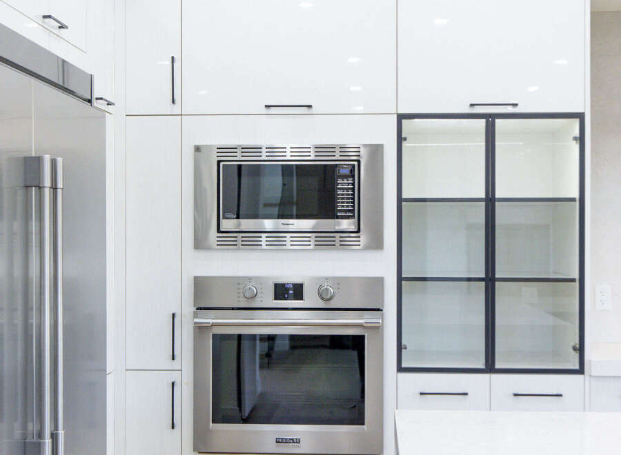 Experience modern luxury in this stunning kitchen, featuring sleek white cabinetry and a built-in stainless steel microwave and oven.