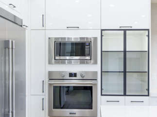 Experience modern luxury in this stunning kitchen, featuring sleek white cabinetry and a built-in stainless steel microwave and oven.