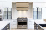 Experience modern luxury in this stunning kitchen, featuring sleek white cabinetry and a sophisticated wood-paneled range hood.