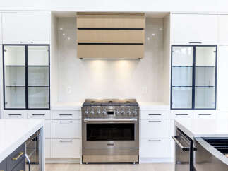 Experience modern luxury in this stunning kitchen, featuring sleek white cabinetry and a sophisticated wood-paneled range hood.