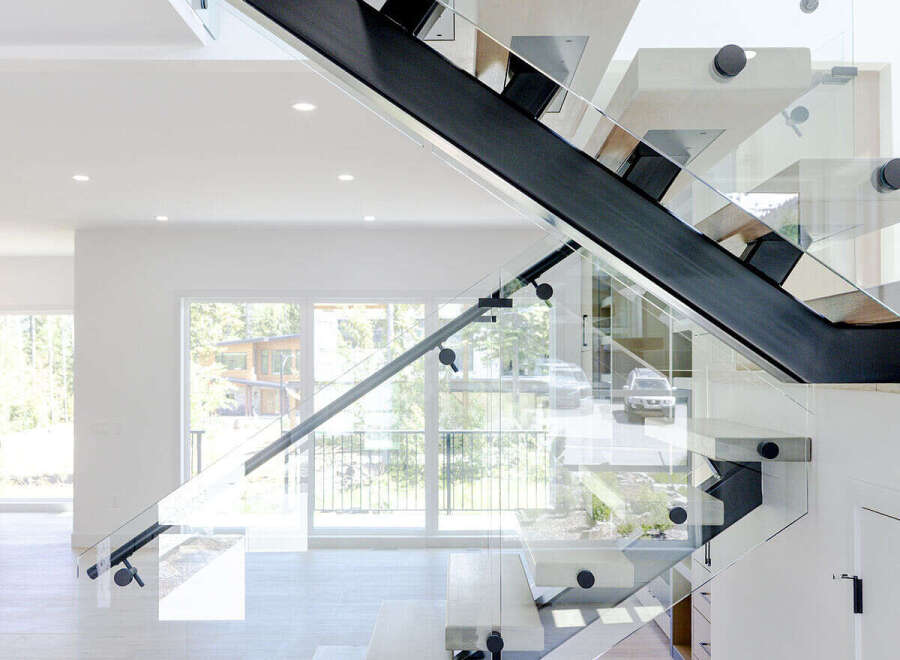 Experience modern luxury with this stunning floating staircase, featuring sleek glass railings and unique cantilevered wood treads.