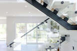 Experience modern luxury with this stunning floating staircase, featuring sleek glass railings and unique cantilevered wood treads.