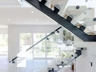 Experience modern luxury with this stunning floating staircase, featuring sleek glass railings and unique cantilevered wood treads.
