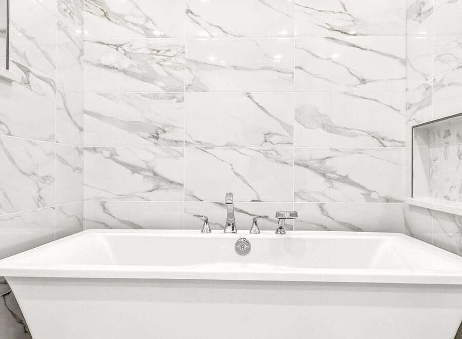 Indulge in luxury with this stunning freestanding bathtub, perfectly complemented by elegant marble-patterned wall tiles.