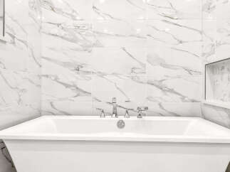 Indulge in luxury with this stunning freestanding bathtub, perfectly complemented by elegant marble-patterned wall tiles.