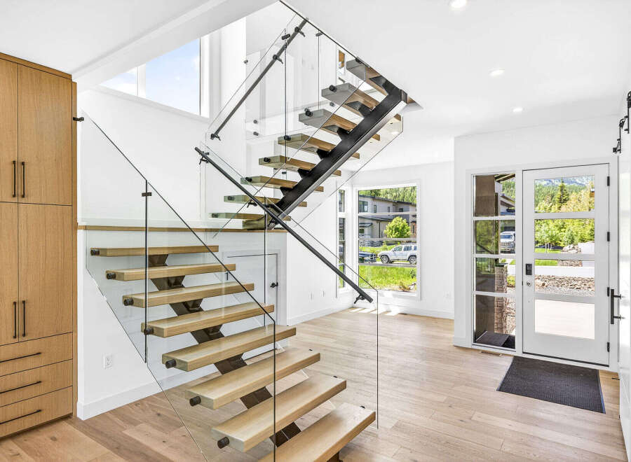 Experience modern living in this stunning home featuring a floating staircase with glass railings and natural wood treads.