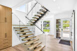 Experience modern living in this stunning home featuring a floating staircase with glass railings and natural wood treads.