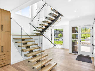 Experience modern living in this stunning home featuring a floating staircase with glass railings and natural wood treads.