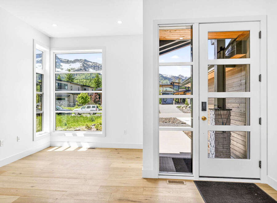Step into this modern entryway featuring a stunning glass-paneled door and expansive windows that flood the space with natural light.