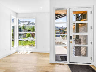 Step into this modern entryway featuring a stunning glass-paneled door and expansive windows that flood the space with natural light.
