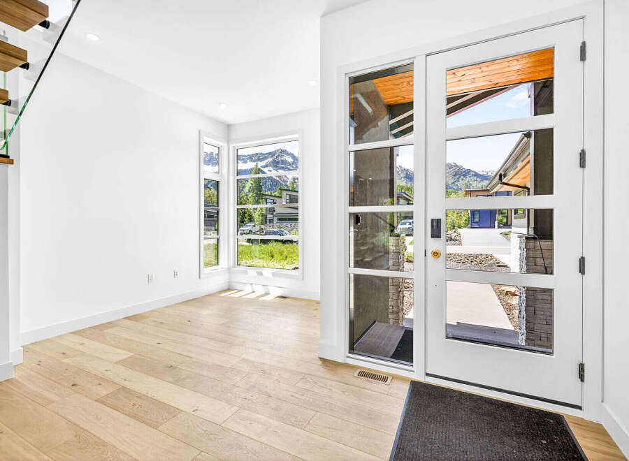Step into this stunning modern entryway featuring a grand glass door that floods the space with natural light.