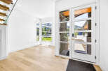 Step into this stunning modern entryway featuring a grand glass door that floods the space with natural light.