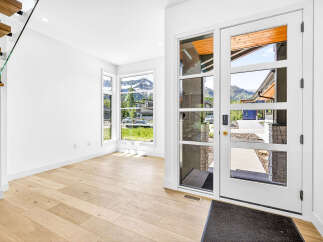 Step into this stunning modern entryway featuring a grand glass door that floods the space with natural light.