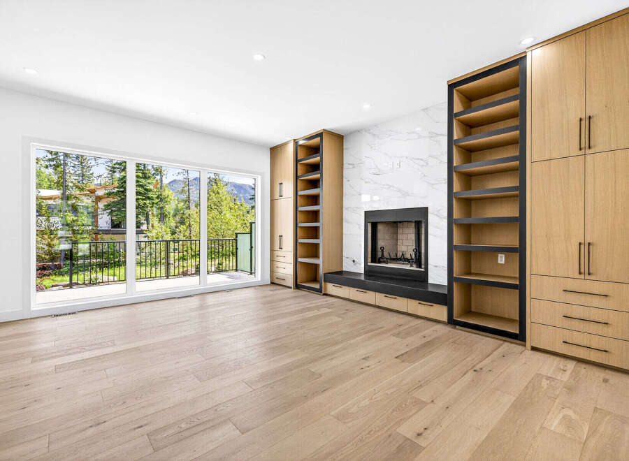 Experience modern living in this spacious room featuring a sleek fireplace with a marble accent wall and custom built-in cabinetry.