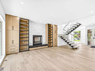 Experience modern luxury in this stunning living room featuring a sleek fireplace with marble surround and custom built-in cabinetry.