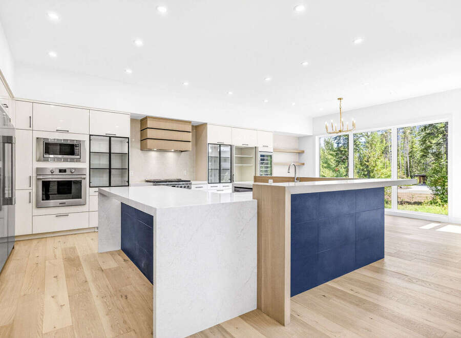Experience modern luxury in this stunning kitchen featuring sleek white cabinetry, integrated stainless steel appliances, and a striking dual island design.