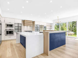 Experience modern luxury in this stunning kitchen featuring sleek white cabinetry, integrated stainless steel appliances, and a striking dual island design.