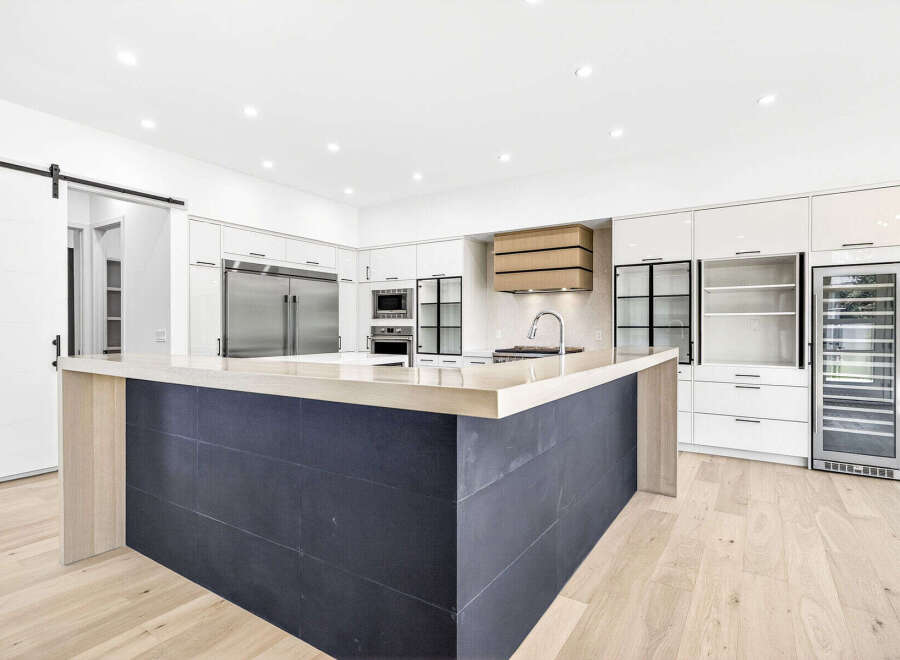 Experience modern luxury in this stunning kitchen, featuring a sleek dark tiled island with a light wood countertop and a matching range hood.