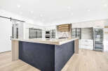Experience modern luxury in this stunning kitchen, featuring a sleek dark tiled island with a light wood countertop and a matching range hood.