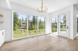 Experience modern living with expansive windows offering breathtaking views of the surrounding nature and a home under construction.