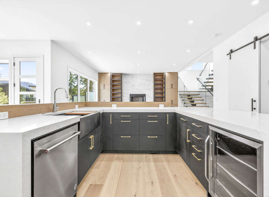 Experience modern luxury in this stunning kitchen, featuring sleek dark cabinetry with elegant gold hardware and a spacious white quartz countertop.