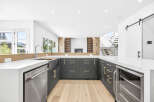 Experience modern luxury in this stunning kitchen, featuring sleek dark cabinetry with elegant gold hardware and a spacious white quartz countertop.