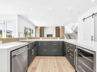 Experience modern luxury in this stunning kitchen, featuring sleek dark cabinetry with elegant gold hardware and a spacious white quartz countertop.