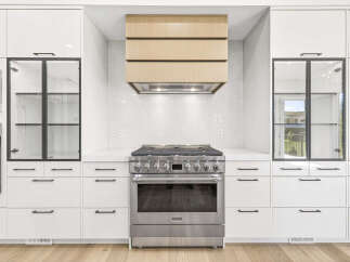 Experience culinary excellence in this modern kitchen, featuring a professional-grade gas range and a sleek, integrated range hood with a warm wood finish.