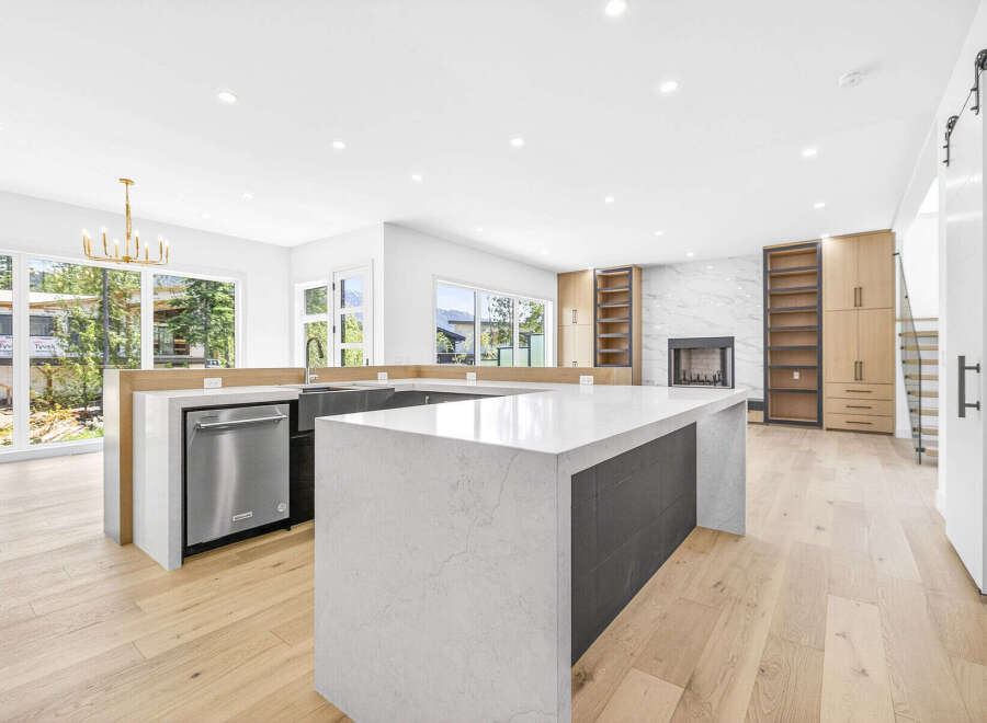 Experience modern luxury in this stunning open-concept kitchen and living area, featuring a sleek waterfall island and a striking marble fireplace.