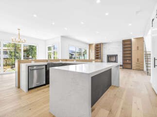 Experience modern luxury in this stunning open-concept kitchen and living area, featuring a sleek waterfall island and a striking marble fireplace.