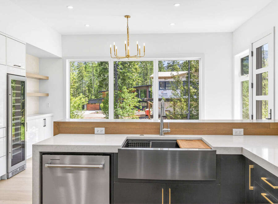 Experience modern luxury in this stunning kitchen, featuring sleek white cabinetry, a built-in wine fridge, and a spacious farmhouse sink.