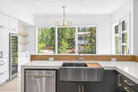 Experience modern luxury in this stunning kitchen, featuring sleek white cabinetry, a built-in wine fridge, and a spacious farmhouse sink.