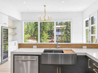 Experience modern luxury in this stunning kitchen, featuring sleek white cabinetry, a built-in wine fridge, and a spacious farmhouse sink.