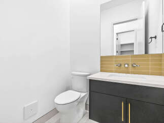 This modern bathroom features a sleek vanity with gold hardware and a white countertop, complemented by a stylish tiled backsplash.