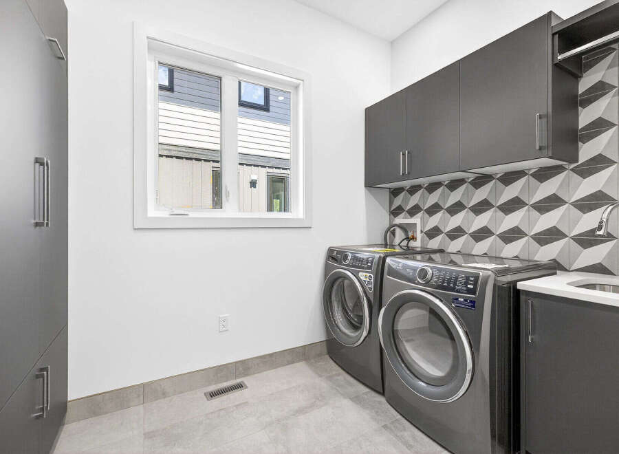 This modern laundry room features sleek dark gray cabinetry, providing ample storage solutions.