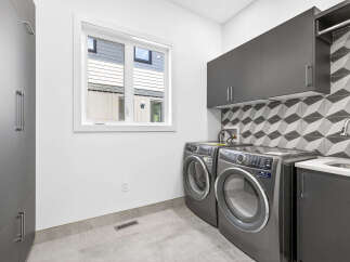 This modern laundry room features sleek dark gray cabinetry, providing ample storage solutions.