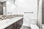 This modern bathroom features a sleek vanity with a white countertop and dark wood cabinets, complemented by a stylish hexagonal tile backsplash.
