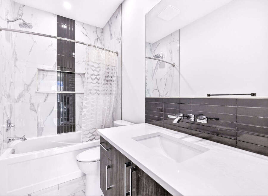 Experience modern luxury in this stunning bathroom, featuring a sleek bathtub and toilet.