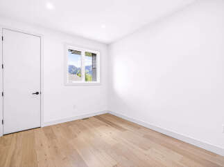 Step into this bright and airy room featuring a modern white door and a large window with stunning mountain views.